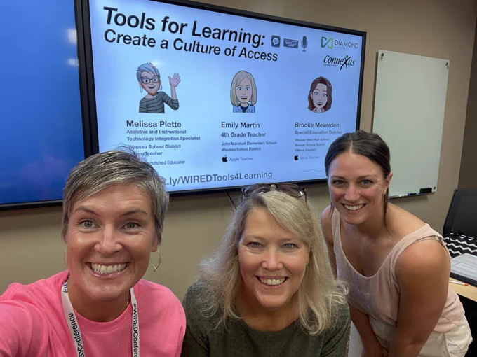 Melissa stands in Front of TV showing start slide of a presentation with Melissa Piette Emily Martin and brooke mother Dan the title on the slide says Tools For Learning Peeps create a culture of access. This is a WIRED Conference Schedule presentation.