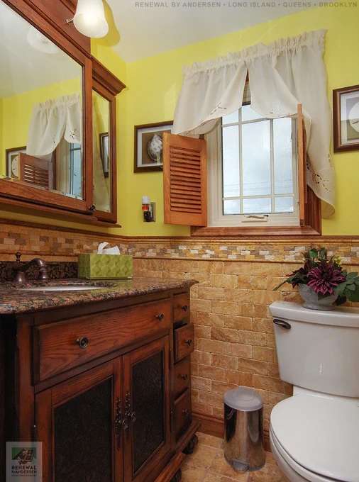 Charming bathroom with new casement window we installed. This gorgeous bathroom with dark wood vanity and custom brick style tile work looks amazing with this new replacement window we installed with prairie style grilles. Replacing your home windows is easy with Renewal by Andersen of Long Island, serving Nassau, Suffolk, Brooklyn and Queens.