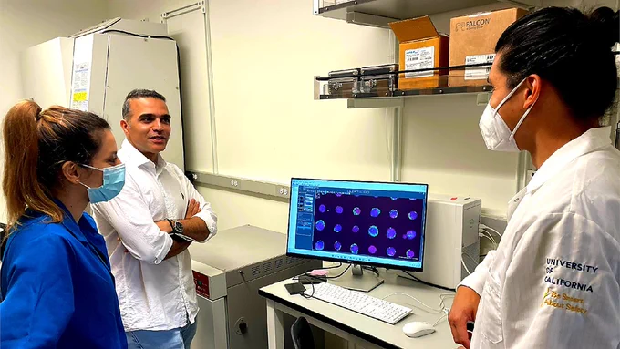 Ali Shariati in his lab discussing research with two of his lab members