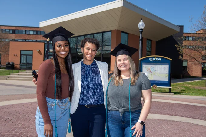 Two students standing with the Dean wearing their Exploratory graduation cords.
