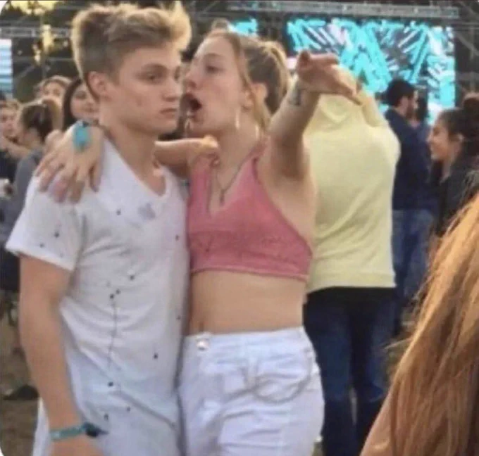 Young woman at a concert yells into the ear of an unenthusiastic young man
