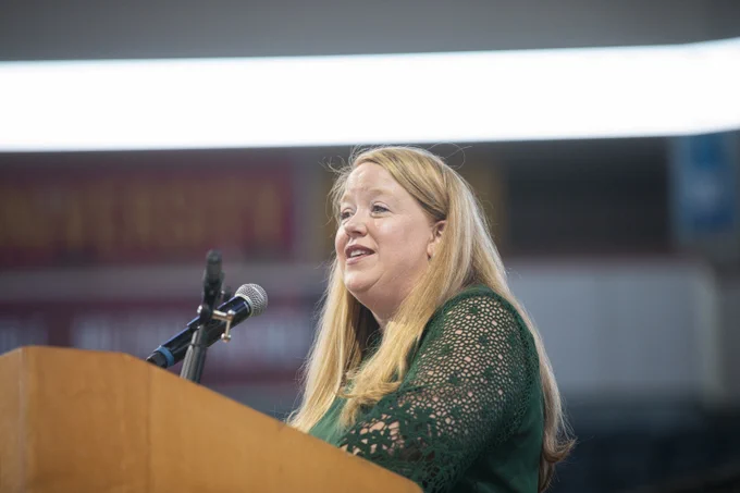 Woman in green dress speaking at podium