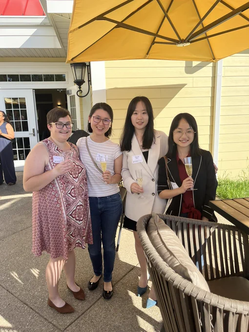 Catherine, Jiayin, Sigrid, and Ranran standing under a yellow patio umbrella