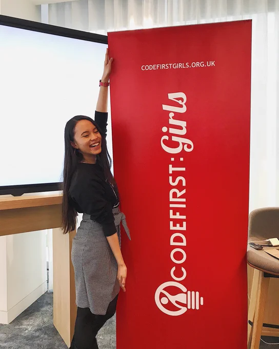 Pauline posing next to the original Code First Girls logo at a conference
