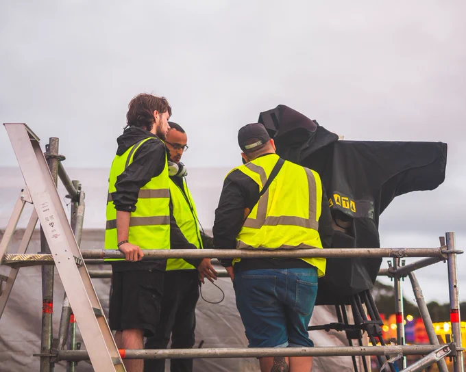 Three Solent Productions crew members standing on the gantry around the front of house camera