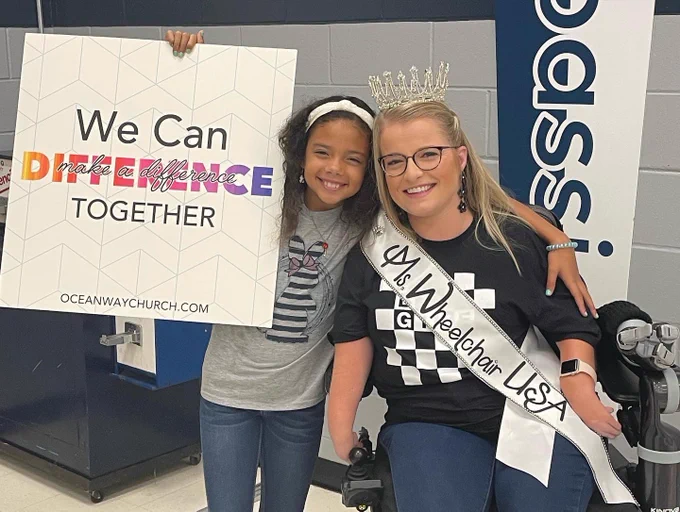 Smiling with a We can make a difference together sign.