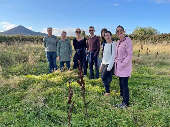 An image of 7 people (2 male, 5 female) standing in an open field conducting research 