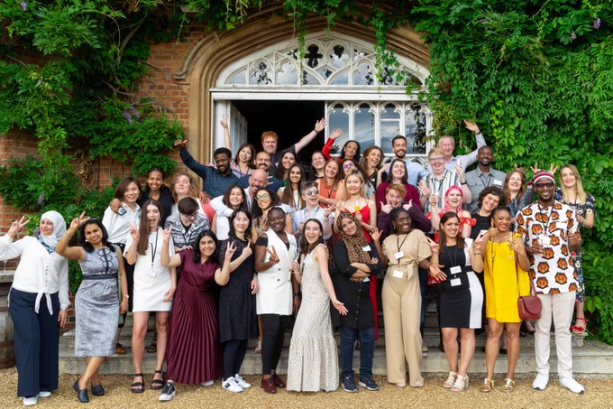 A group photo of the conference delegates on the steps outside the Tapestry Hall door, making fun poses.