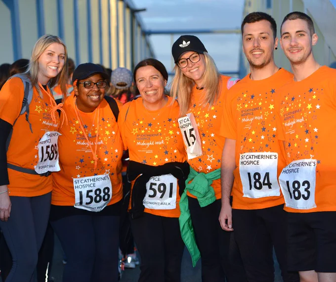 Group of six walkers wearing orange MNW t-shirts and registration numbers, all smiling at the camera. 