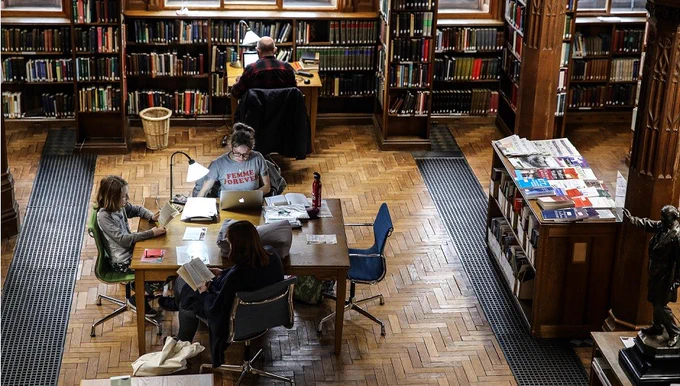 A group of young people studying at the tables on the ground floor of the Reading Rooms.