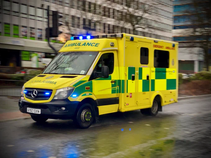 Ambulance responding to an emergency, driving down a city road.