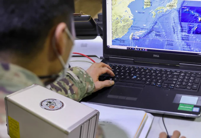A Soldier looking at a map on a laptop computer, with a portable drive in the foreground. (Photo Credit: U.S. Army)