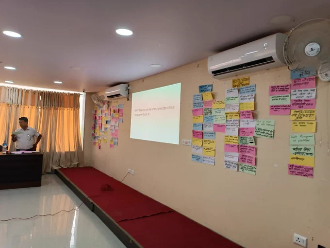 A wall showing lots of coloured sheets of paper with writing on them