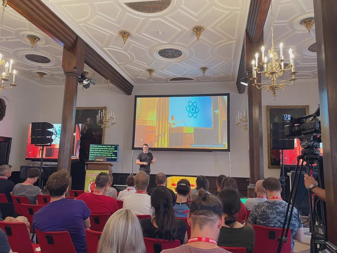 Manuel on stage with a picture of him on stage at React Finland 2019.