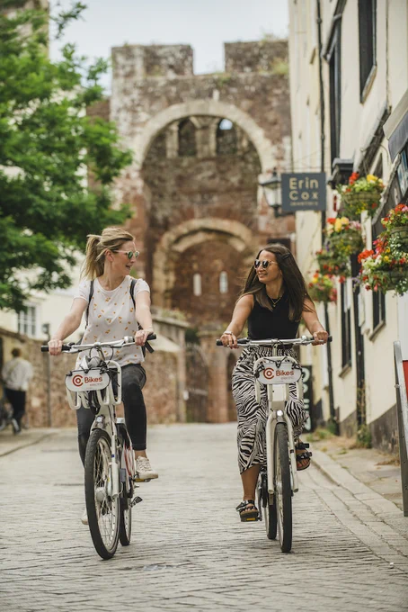 Photo of two women riding CoBikes along an Exeter street