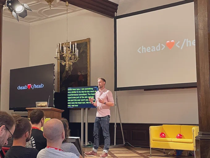 Harry Roberts on stage; a slide of his presentation showing „<head>❤️</head>