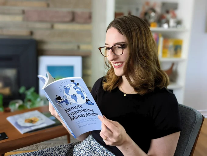 A picture of me sitting in a chair holding my book, flipping through the pages and smiling.
