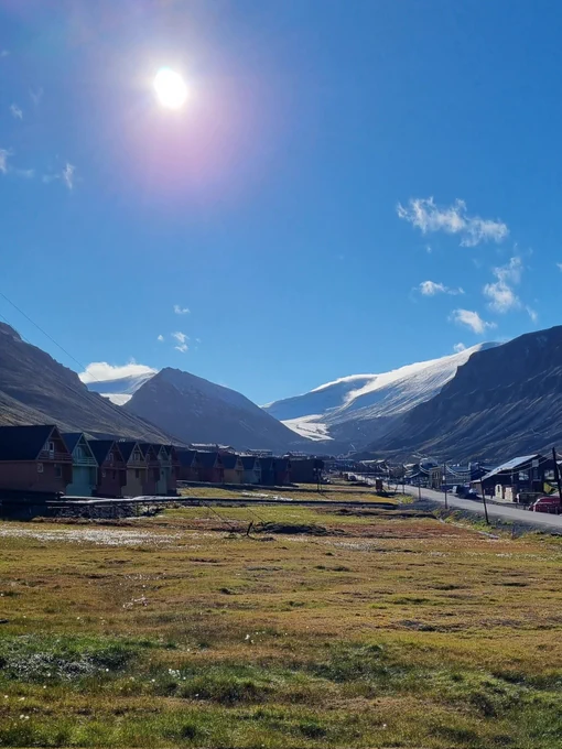 Colourful huts with glacier in the distance and sunny blue sky