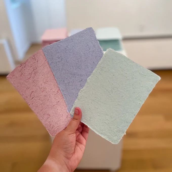 hand holding up 3 sheets of scrubs paper in the gallery. There is a pink sheet, blue sheet, and a green sheet.