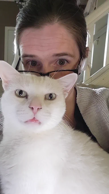 Daniece in the background with her fluffy white cat, Pixel, in the foreground.
