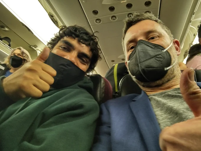 Two guys on a plane wearing masks. 1 is Logie winning cool dude, 1 is me.
