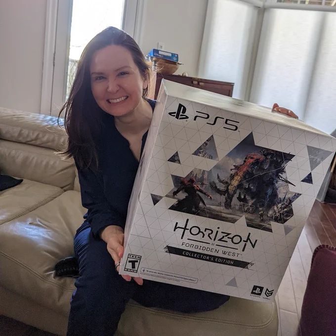 Michelle Lovretta grins while holding a collector's edition box for one of the video games in the Horizon Zero Dawn series.