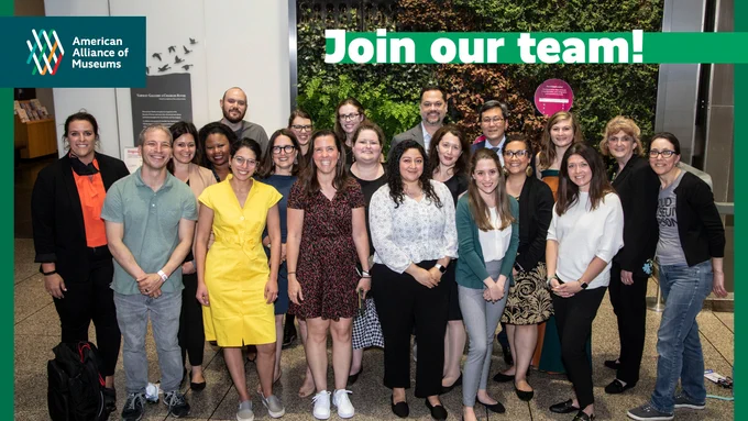 AAM staff lined up for a group photo in front of a living green wall at Boston Museum of Science during the 2022 AAM Annual Meeting & MuseumExpo. Overlain text on the photo reads: Join our team!