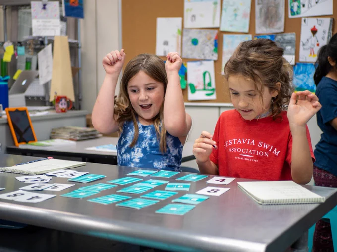Two students celebrate after finding the correct answer in a math skills game.