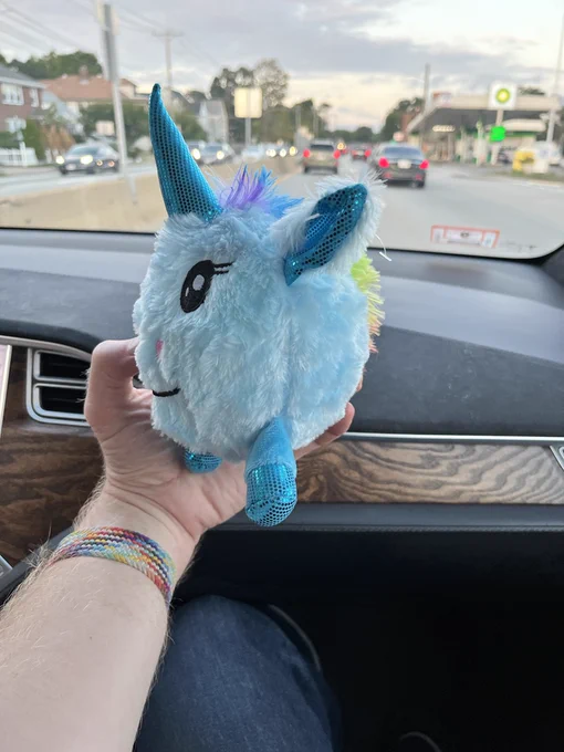 A round blue fuzzy unicorn ball stuffy, with its two legs oddly forward