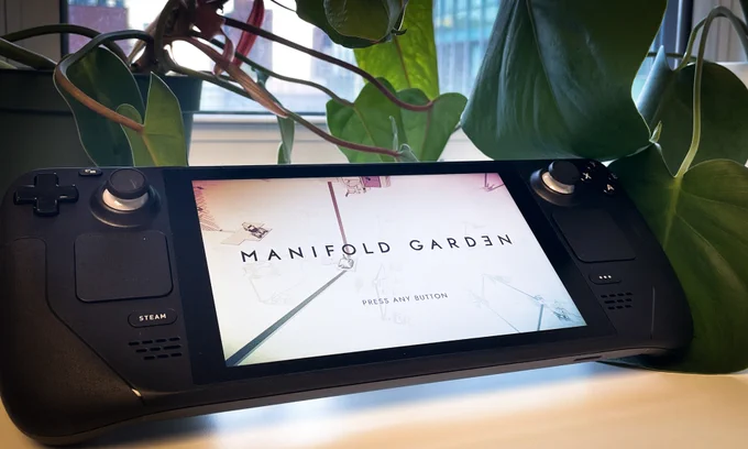 Steam Deck showing Manifold Garden title screen in front of plants. 