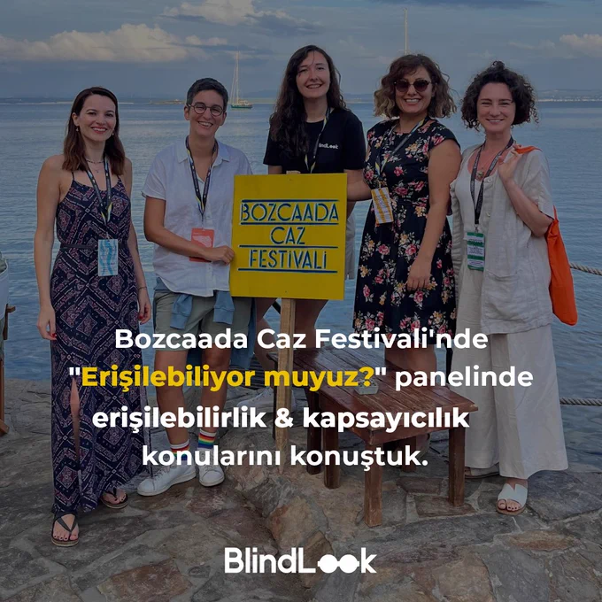 Görselde 5 tane kadın kameraya doğru gülümsemektedir. BlindLook tshirtlü uzun saçlı uzun boylu kadın  “bozcaada caz festivali” yazılı bir pankart tutmamaktadır. Fotoğrafın üzerinde BlindLook logosu ile beraber “Bozcaada Caz Festivali'nde "Erişilebiliyor muyuz?" panelinde erişilebilirlik & kapsayıcılık konularını konuştuk.” Yazmaktadır.