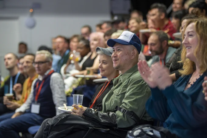 An audience smiles and claps