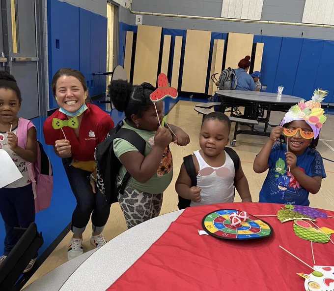 Young learners smiling, making back-to-school masks in the cafeteria