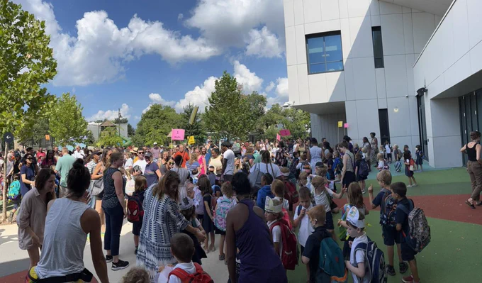A large crowd celebrating in front of Maury Elementary School on a sunny day 