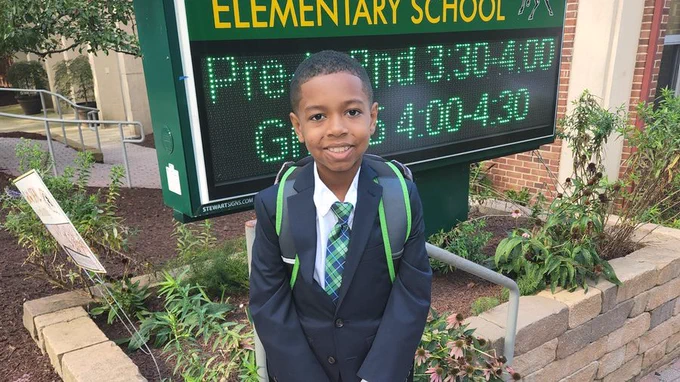A young scholar shows off his suit and tie at Shepherd Elementary School