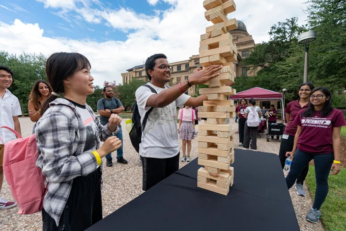 students playing jenga on a table in academic plaza.