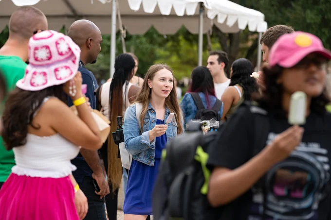 students standing in academic plaza talking and eating popsicles.
