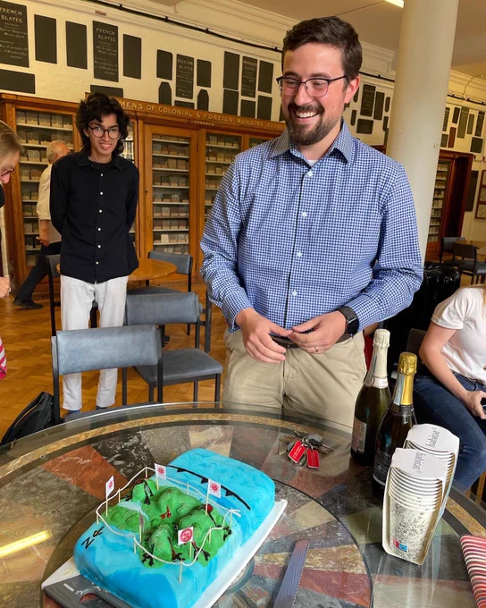 Nick barber standing in front of a cake with people in the background
