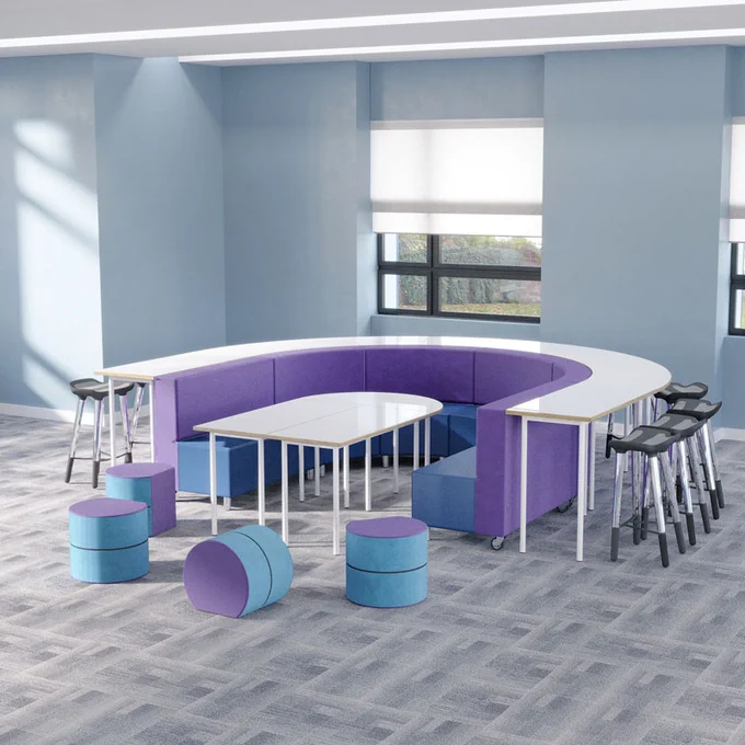 12 Beparta Stools (medium height) are arranged around perch tables. The stools and tables form a horseshoe shape. Inside the tables, upholstered lounges with high backs are arranged in the same shape, the backs of all the lounges neatly fit against the tables. 4 ottomans are shown, they can be used as seating. The ottomans allow students to gently rock or sit on them in multiple different ways. There are tables in the centre, again in a horseshoe shape, which can be used by the students who sit on the lounges or the ottomans. The tables have writeable surfaces.