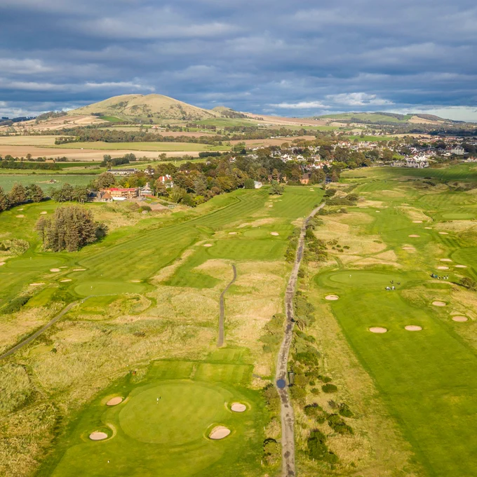 Image shows an aerial view of Lundin Golf Club in Lundin Links, on the south coast of Fife, with the hill of Largo Law in the distance