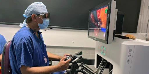 A doctor sits at the robotic console looking at the camera screen mid surgery.