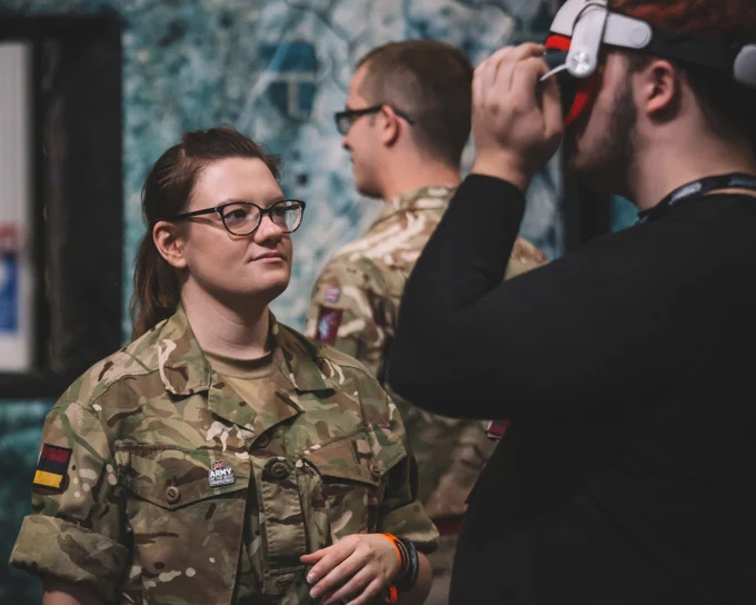 Soldier helping someone with virtual reality headset.