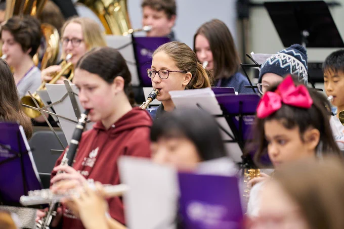 Young musicians playing band instruments together with Western Music students