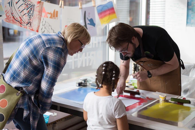 Three people, one of them a child, at a print workshop.