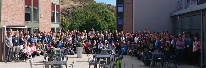A large group of delegates on a patio, all looking at the camera