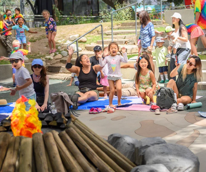 Children and adults singing around a pretend campfire