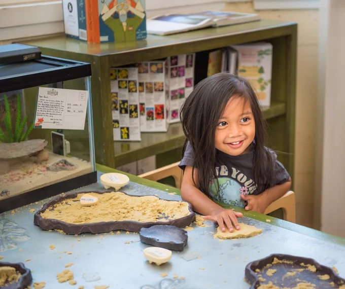 Child playing at a table with sand and animal track prints