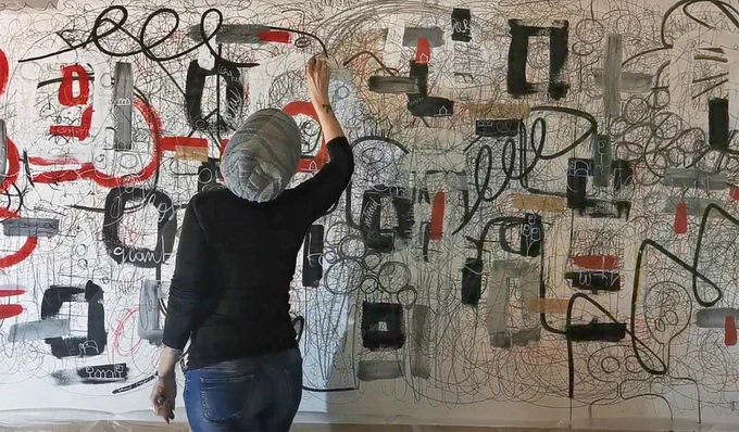 Artist drawing on a wall creating a large-scale abstract artwork