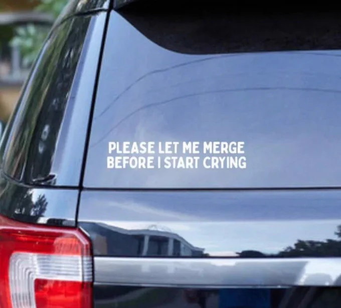 Picture of the back of a blue SUV and the sticker on the back windshield says please let me merge before I start crying