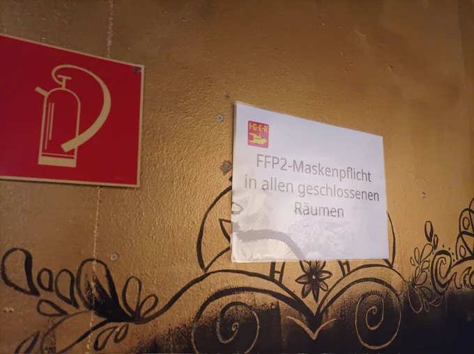 Ein Schild am Eingang mit dem Hinweis "FFP2-Maskenpflicht in allen geschlossenen Räumen" oben rechts ist das Logo der IGER 2022